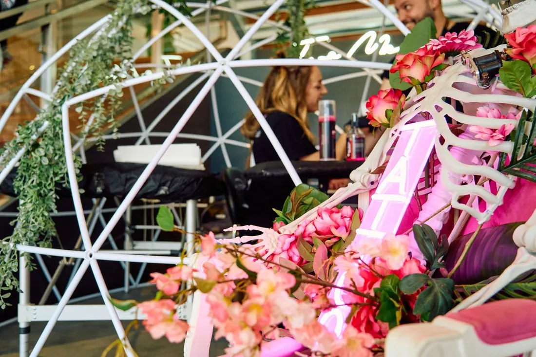 Detalle del stand en un evento: cúpula, Sarai tatuando y decoración de flores